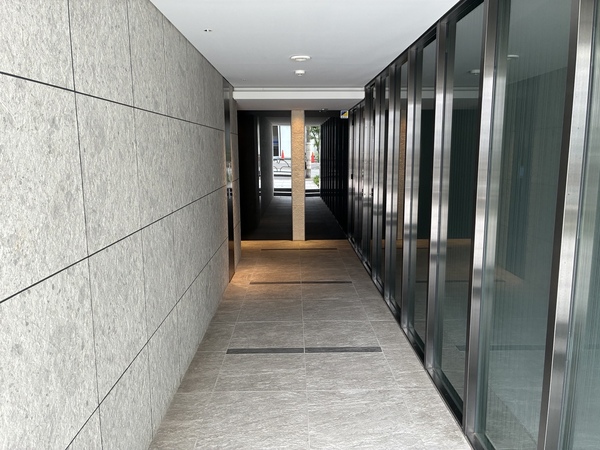 奥行あるエントランスアプローチ。脇にはガラスカーテンウォールを施しひと味違う空間演出となっています