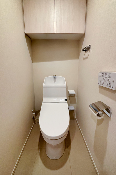 温水洗浄便座採用のトイレ。吊戸棚にはトイレットペーパーや掃除洗剤などの消耗品が収納できて便利です。